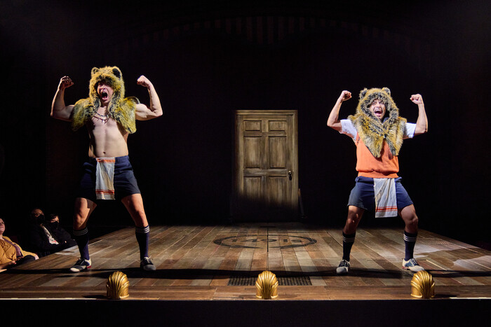 Two performers wearing bear hoods dance onstage.